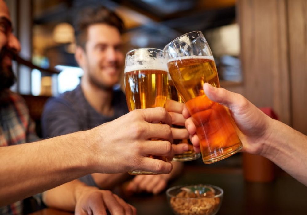 happy male friends drinking beer at bar or pub people, men, leisure, friendship and celebration concept - happy male friends drinking beer and clinking glasses at bar or pub